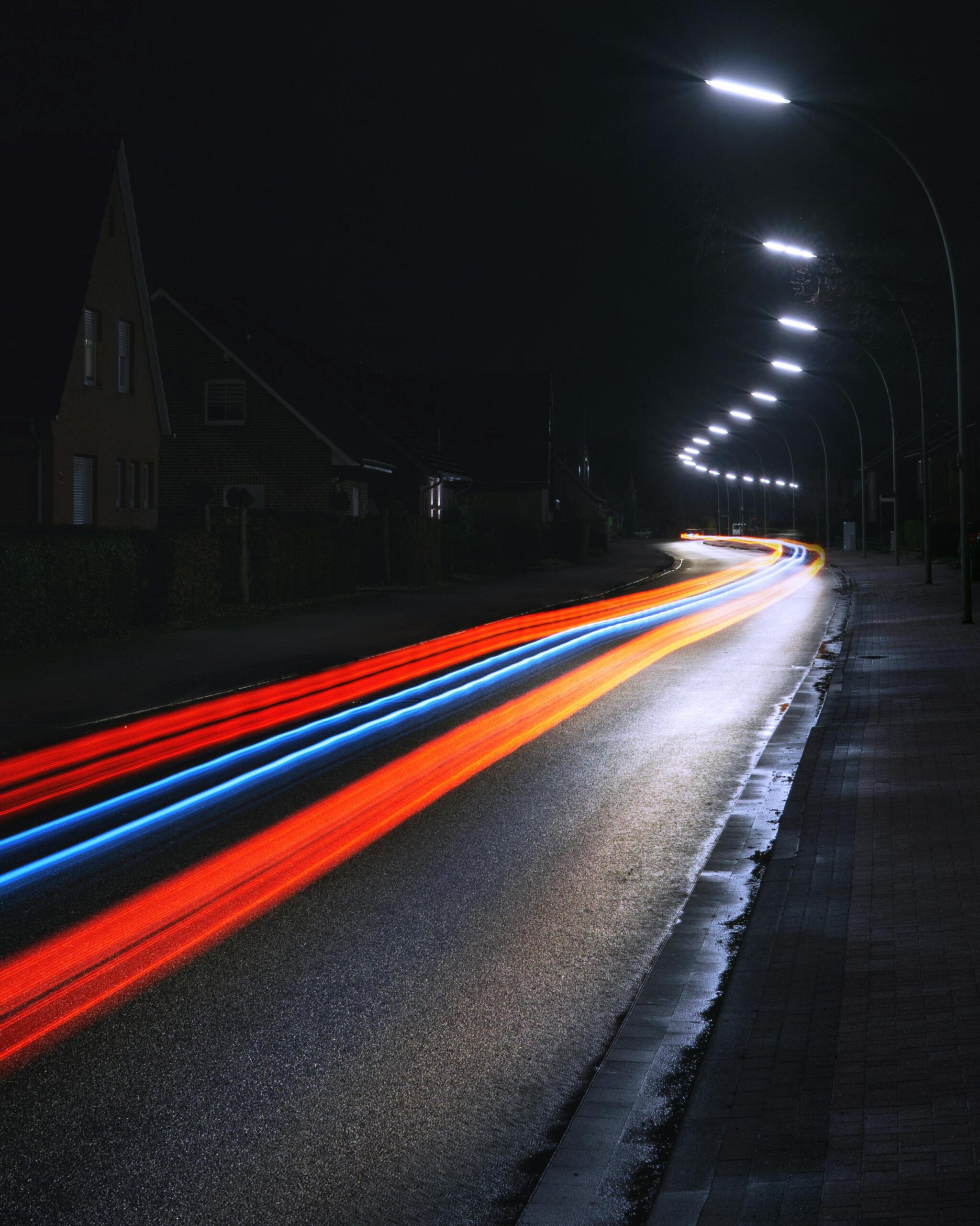 Long exposure of vibrant light trails on a city street at night, showcasing motion and speed.